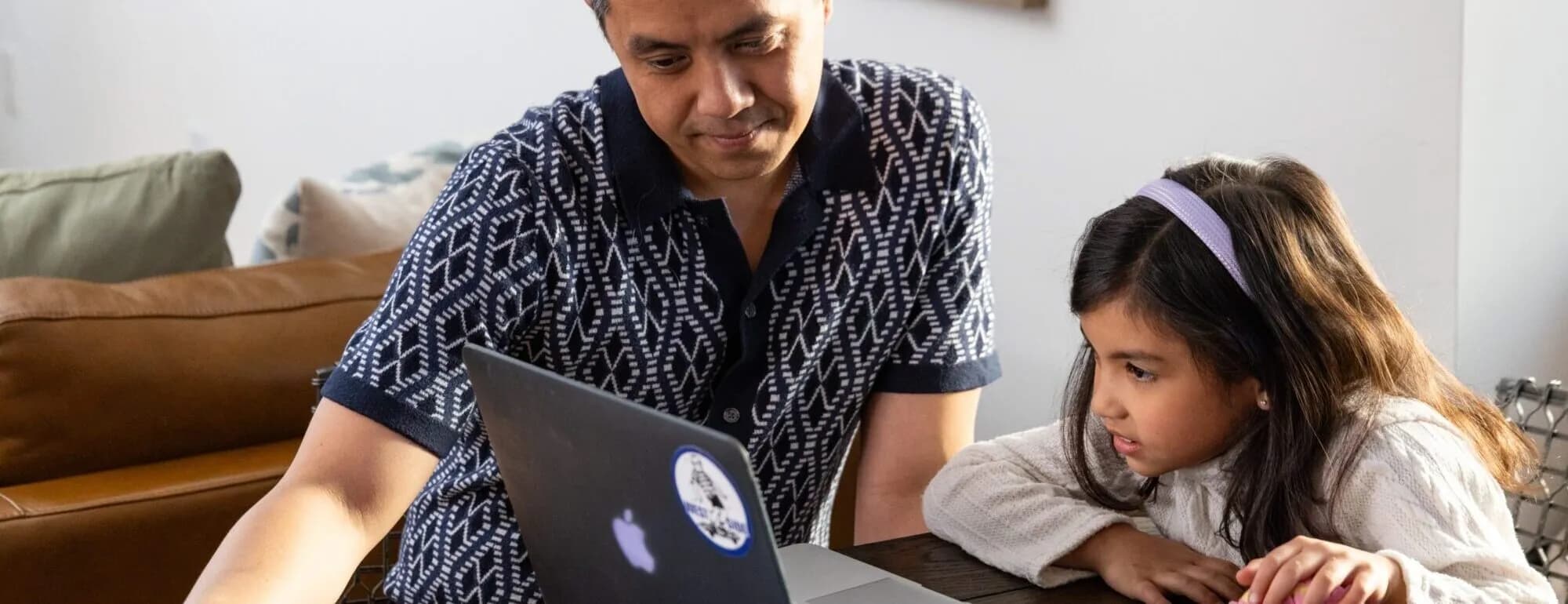 A parent and a young student looking at a laptop together at home